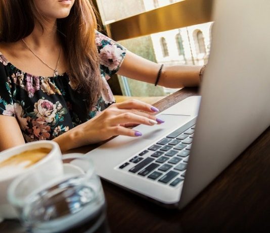 Santa Catarina é o estado com menor taxa de desocupação entre mulheres mulher trabalhando no notebook com xícara de café ao lado