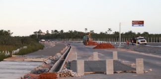 blocos de concreto e montes de areia sobre rodovia nova; ao lado pista em construção