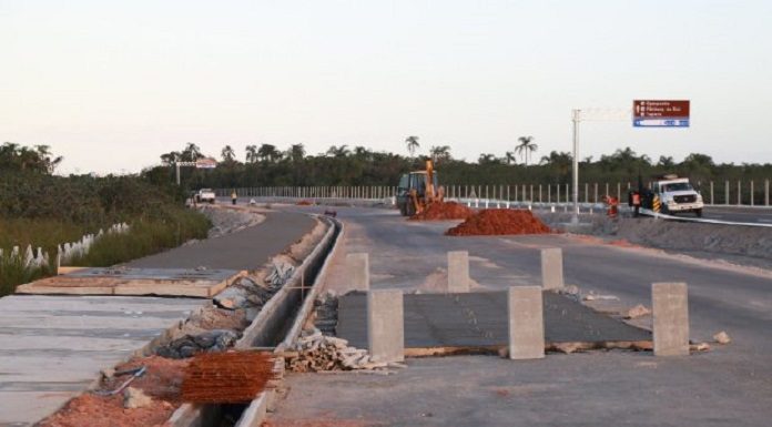 blocos de concreto e montes de areia sobre rodovia nova; ao lado pista em construção