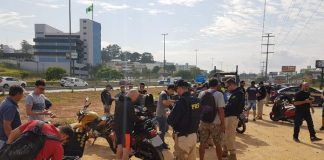 diversas motos paradas em terreno com motociclistas e policias em volta