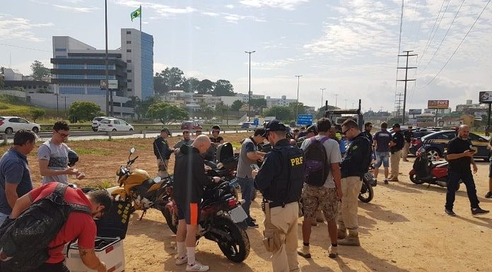 diversas motos paradas em terreno com motociclistas e policias em volta