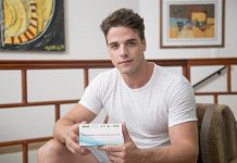 homem olha para a câmera segurando um teste oral rápido de hiv