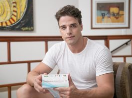 Campanha em Florianópolis intensifica esforços na prevenção ao HIV homem olha para a câmera segurando um teste oral rápido de hiv