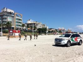 carro ford edge da pm na faixa de areia de canasvieiras com cinco policiais andando e prédios ao fundo