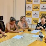 prefeita e secretárias reunidas em volta de uma mesa e painel com logos de são josé ao fundo