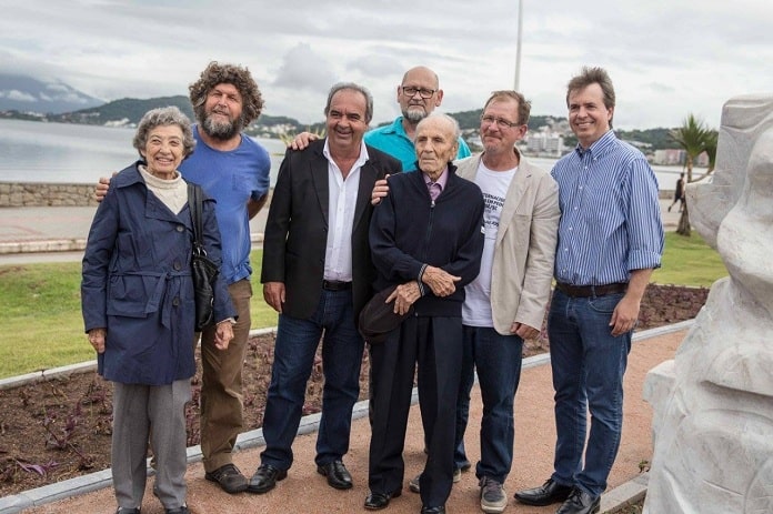 grupo posando para foto com pléticos no meio na beira-mar de são josé