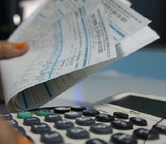 pessoa segura contas de água ao lado de uma calculadora