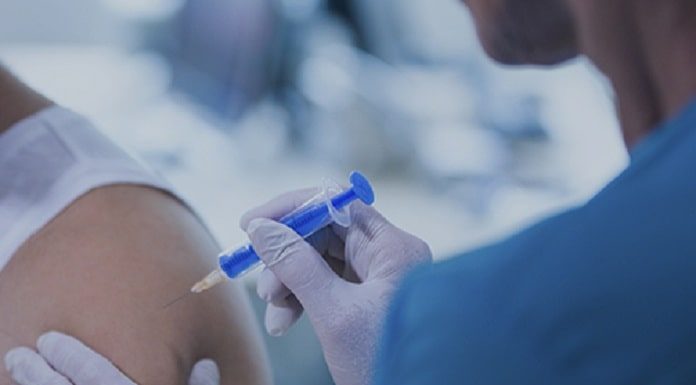 pessoa aplica vacina no braço de um homem