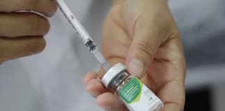 mão com seringa pegando vacina do frasco