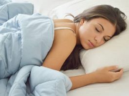 mulher dormindo em uma cama, coberta com um cobertor azul
