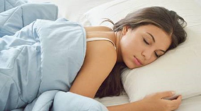 mulher dormindo em uma cama, coberta com um cobertor azul