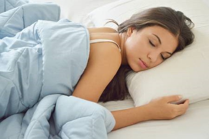 mulher dormindo em uma cama, coberta com um cobertor azul