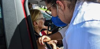 Enfermeira aplicando vacina no braço de idosa