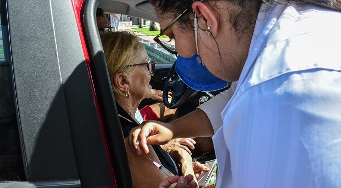 Enfermeira aplicando vacina no braço de idosa