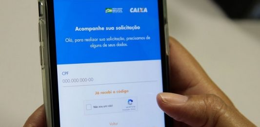 pessoa segura celular com aplicativo da caixa aberto na tela
