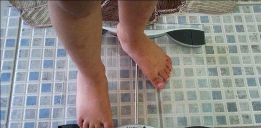 Pessoa se pesando numa balança