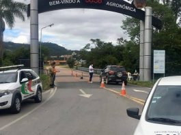 Grupo de reabertura vai discutir pequenos municípios e ensino à distância em SC carro parado no sob o portal da cidade onde há cones na estrada e um homem de máscara ao lado do carro; carro da polícia; mais três pessoas em volta