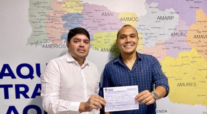 clonny capistrano e manoel galeno posam para a foto segurando juntos a ficha de filiação; há um mapa de sc na parede