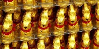 diversos coelhos de chocolates embalados em papel dourado enfileirados em prateleiras