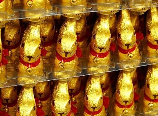 diversos coelhos de chocolates embalados em papel dourado enfileirados em prateleiras