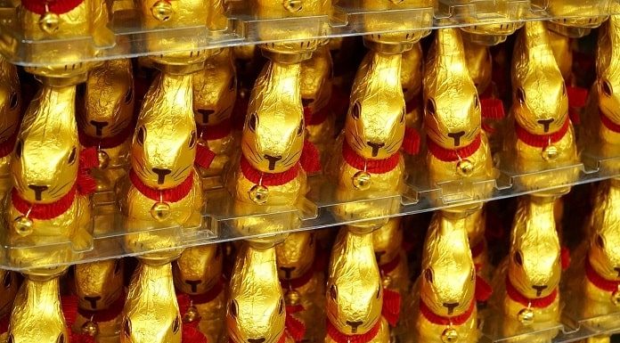 diversos coelhos de chocolates embalados em papel dourado enfileirados em prateleiras