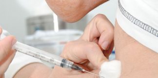 pessoa aplica injeção de vacina no braço de outra