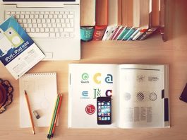 celular, livro aberto, lápis, borracha, livros fechados e notebook visto de cima organizados sobre mesa