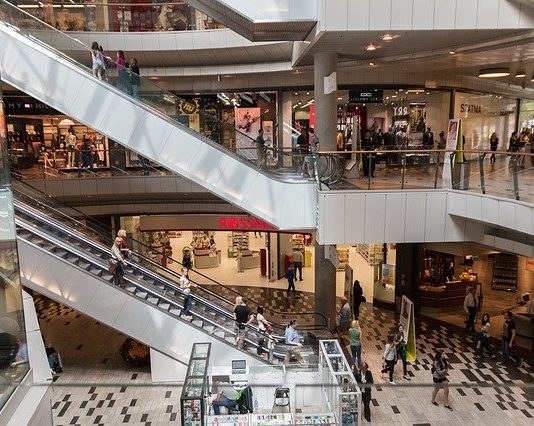 Os regramentos para shoppings, academias e restaurantes reabrirem em SC área central de um shopping com pessoas em escadas rolantes