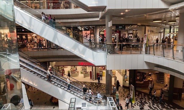 área central de um shopping com pessoas em escadas rolantes