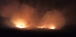 incêndio visto à distância em meio a grande área escura com muita fumaça