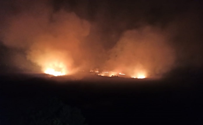 incêndio visto à distância em meio a grande área escura com muita fumaça