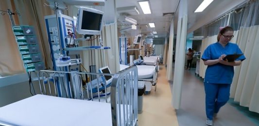 UTIs pediátricas do SUS lotam e governo de SC anuncia ampliação profissional de saúde andando no corredor de uti com leitos expostos pelas cortinas recolhidass