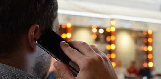 homem visto de costas falando ao celular