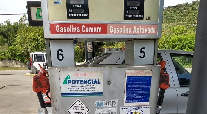 Fiscais do Procon colando adesivo na bomba de gasolina