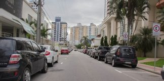 carros estacionados em rua de mão única no bairro campinas e foto tirada no meio da rua, com prédios em volta
