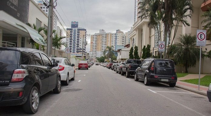 carros estacionados em rua de mão única no bairro campinas e foto tirada no meio da rua, com prédios em volta