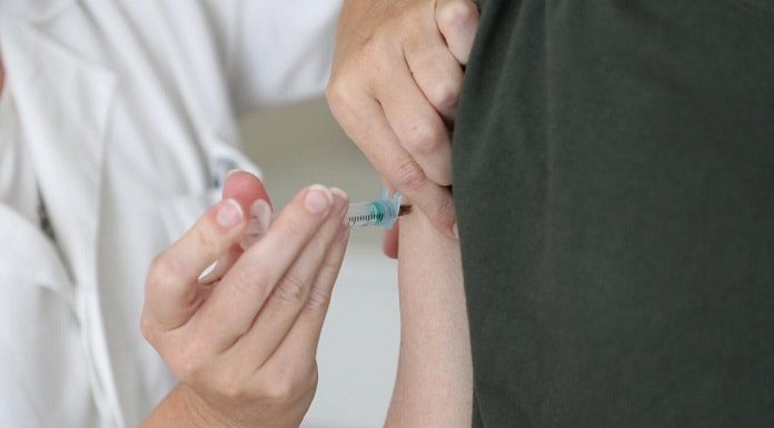 pessoa aplica injeção de vacina no braço de outra