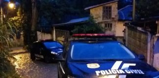 gm edge e ford fiesta da polícia civil estacionados em ladeira estreita molhada de chuva com pequenas casas ao lado; rua em curva; amanhecendo