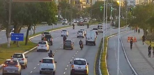 Liberações ao comércio em SC adicionaram mais de 700 mil pessoas nas ruas imagem de câmera de rua na avenida beira-mar mostrando carros passando e algumas pessoas no calçadão