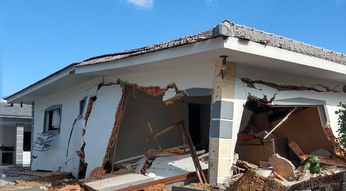 casa com grandes rachaduras e praticamente destruída, com detritos espalhados