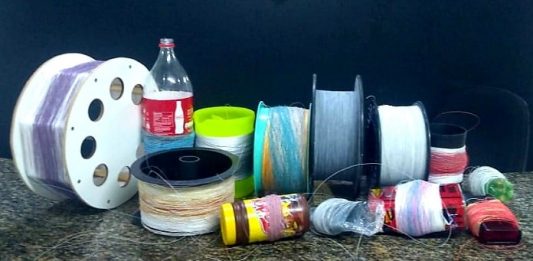 Linhas com cerol são apreendidas na Coloninha carreteis de diferentes cores e tamanhos com as linhas enroladas organizados sobre uma bancada; um deles é uma garrafa de coca-cola