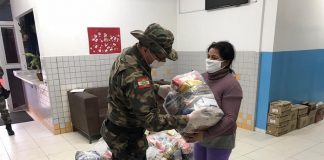 Policial militar entregando alimentos a uma senhora