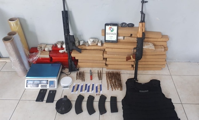 metralhadoras, tabletes de maconha e munições e outras tralhas organizados no chão