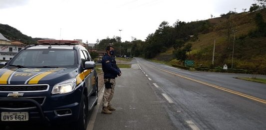 PRF flagra 237 motoristas ultrapassando em local proibido policial Rodoviário Federal de pé ao lado da viatura