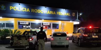 policial de costas ao lado dos carros parados em frente ao posto da prf à noite