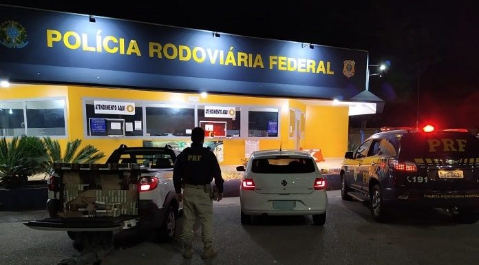 policial de costas ao lado dos carros parados em frente ao posto da prf à noite