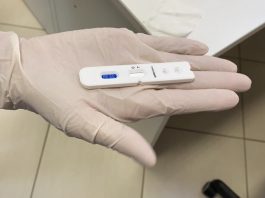 pessoa usando luva mostra teste de coronavirus sobre a palma aberta