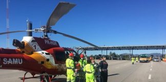 helicóptero taxiado na pista em frente ao pedágio com equipes de resgate em volta