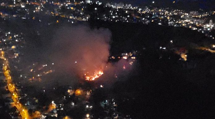 foto aérea em área escura com foco de incêndio no meio e luzes de residências em volta