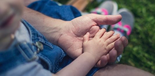 SC teve 435 adoções de crianças e adolescentes em 2019 close em criança com a mãozinha sobre a mão de um homem adulto